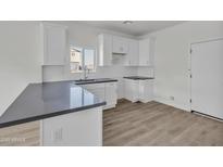 Well-lit kitchen featuring white cabinets, gray countertops, and modern fixtures at 1250 E Wood St # 30, Phoenix, AZ 85040
