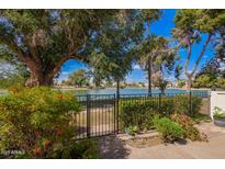 Serene backyard view with mature trees and gate leading to a tranquil lake setting at 2714 W Desert Cove Ave, Phoenix, AZ 85029