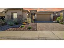 Beautiful single-story home showcasing desert landscaping, a paver driveway, and a two-car garage at 32297 N 133Rd Ln, Peoria, AZ 85383