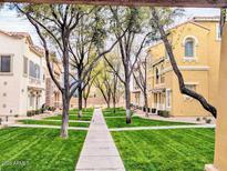 Well-maintained community lawn and sidewalk with mature trees and attractive townhome exteriors at 419 N Alder St, Gilbert, AZ 85233