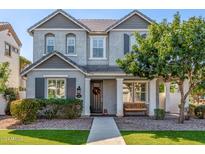 Charming two-story home featuring gray stucco, dark trim, a welcoming front porch, and manicured landscaping at 10451 E Natal Ave, Mesa, AZ 85209