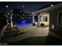 Cozy backyard with a private pool, patio area, and lounge chairs for relaxation beneath decorative string lights at 21359 E Camacho Rd, Queen Creek, AZ 85142