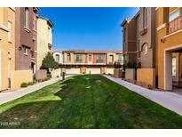 Inviting townhome community featuring a green lawn and well-maintained exteriors on a beautiful sunny day at 240 W Juniper Ave # 1146, Gilbert, AZ 85233