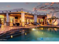Backyard features a swimming pool, covered patio with lounge seating, and meticulous desert landscaping under a twilight sky at 4438 E Millbrae Ln, Gilbert, AZ 85234