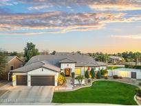 Beautiful single-story home featuring manicured landscaping, a three-car garage, and elegant exterior lighting at 479 E Horseshoe Pl, Chandler, AZ 85249