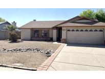 Charming single-story home featuring a gravel front yard and a two-car garage with decorative windows at 8815 W Orchid Ln, Peoria, AZ 85345