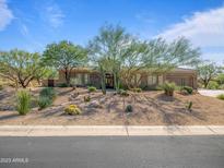 Inviting desert home with lush xeriscaping, mature trees, and charming curb appeal at 10829 E Volterra Ct, Scottsdale, AZ 85262