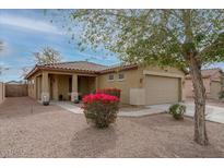 Charming single-story home featuring desert landscaping, a two-car garage and vibrant blooming shrubs at 25067 W Dove Trl, Buckeye, AZ 85326