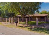 Charming single-story home featuring a secure fence, mature trees, and well-manicured lawn at 7216 W Country Gables Dr, Peoria, AZ 85381