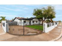 Charming home featuring a black iron fence, well-manicured lawn, and mature trees at 833 S Toltec --, Mesa, AZ 85204