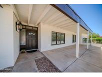Inviting front entrance with a covered porch, a decorative door, and charming exterior lighting at 10105 E Cactus Rd, Scottsdale, AZ 85260