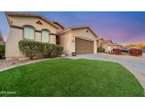 Charming home featuring a manicured lawn, desert landscaping, and a two-car garage at 10772 W Woodland Ave, Avondale, AZ 85323