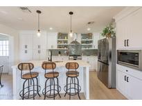 Bright kitchen with island seating, stainless appliances, and stylish backsplash at 3015 E Dahlia Dr, Phoenix, AZ 85032