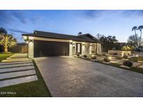 Beautifully landscaped home featuring a modern black garage door and inviting walkway with desert landscaping at 8409 E Clarendon Ave, Scottsdale, AZ 85251