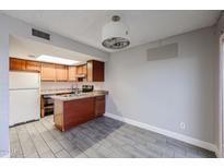 Charming kitchen features wood cabinets, a convenient island, and modern appliances at 10411 N 11Th Ave # 28, Phoenix, AZ 85021