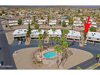 Aerial view showcases the community pool and surrounding two-story condos with mature palm trees, providing a lush desert oasis at 17031 E Calle Del Oro -- # B, Fountain Hills, AZ 85268