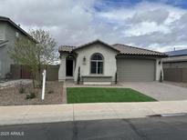 Charming single-story home featuring a desert landscape, lush green lawn, and a two-car garage at 41260 W Palmyra Ln, Maricopa, AZ 85138