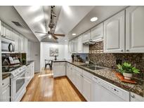 Bright kitchen featuring granite counters, white cabinets, stainless steel sink, and hardwood floors at 6310 E Avalon Dr, Scottsdale, AZ 85251