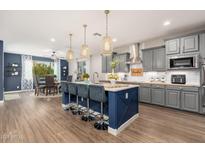 A spacious kitchen with a large center island, wood countertops, stainless appliances, and pendant lighting at 20088 E Maya Rd, Queen Creek, AZ 85142