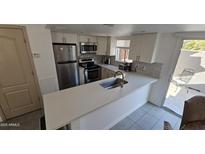 Modern kitchen features stainless steel appliances, a breakfast bar, and opens to a patio at 239 E Betty Elyse Ln, Phoenix, AZ 85022