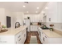 Bright kitchen with white cabinets, stainless steel appliances, a farmhouse sink, and wood floors at 24812 S Pleasant Ct, Sun Lakes, AZ 85248