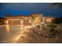 Inviting home exterior featuring a three-car garage and desert landscaping illuminated at twilight at 17642 N Ironhorse Dr, Surprise, AZ 85374