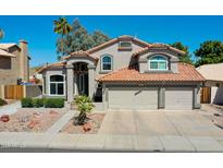 Charming two-story home featuring a red tile roof and a three-car garage, set against a clear blue sky at 19277 N 78Th Ln, Glendale, AZ 85308