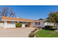 Charming single-story home with white brick and shutters, manicured lawn, and orange tree at 4510 W Keim Dr, Glendale, AZ 85301