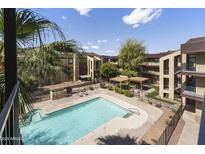 Aerial view of a pool with lounge seating surrounded by well-maintained landscaping and community buildings at 461 W Holmes Ave # 383, Mesa, AZ 85210