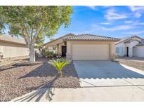 Inviting single-story home with desert landscaping, a mature shade tree, and a neutral-toned facade with a tiled roof at 9231 E Carmel Ave, Mesa, AZ 85208