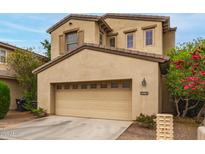 Tan two-story home featuring an attached two-car garage, neutral colors, and desert landscaping at 15239 W Alexandria Way, Surprise, AZ 85379