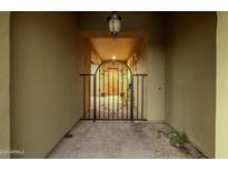 Inviting gated entryway with brick pavers, neutral stucco walls, and an arched gate to the front door at 18068 W Narramore Rd, Goodyear, AZ 85338