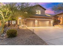 Charming home featuring a well-manicured landscape, stone accents, and a three-car garage under a gorgeous twilight sky at 16044 N 106Th Way, Scottsdale, AZ 85255