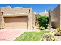 Charming tan home with a well-manicured front yard, desert landscaping, and a two-car garage at 7955 E Chaparral Rd # 120, Scottsdale, AZ 85250