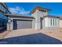 Beautiful single-story home featuring a gray exterior, gray garage door, desert landscaping and a paver driveway at 21422 W Meadowbrook Ave, Buckeye, AZ 85396