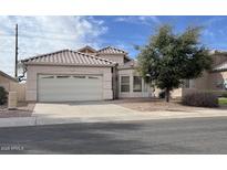 Tan single-story home featuring a two-car garage and tile roof in a quiet neighborhood at 1009 E Brentrup Dr, Tempe, AZ 85283