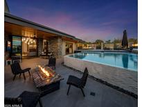 Stunning backyard with fire pit, outdoor seating, and a gorgeous pool with water features at 10381 E Loving Tree Ln, Scottsdale, AZ 85262