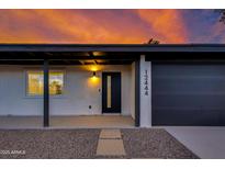 Close-up of house with dark front door and garage under a dramatic sky with decorative rock landscape at 12444 N 33Rd St, Phoenix, AZ 85032