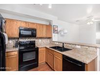The kitchen features wood cabinets, granite countertops, black appliances, and a double sink at 34924 N 30Th Ave, Phoenix, AZ 85086