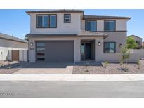 Inviting two-story home featuring a gray garage door, well-maintained gravel yard, and a modern architectural design at 40113 N Alameda Dr, San Tan Valley, AZ 85140