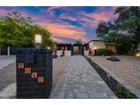 Charming single-story home featuring desert landscaping, block wall, and illuminated walkway to the front door at 7042 N 12Th Way, Phoenix, AZ 85020