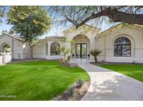 Inviting home exterior with lush lawn, tiled walkway, and arched entryway providing curb appeal at 7157 E Bronco Dr, Paradise Valley, AZ 85253