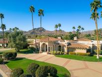 Stunning aerial view of a luxury estate home with lush landscaping, circular drive and mature palm trees at 8712 N 64Th Pl, Paradise Valley, AZ 85253