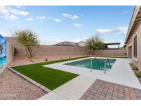 Beautiful backyard featuring a sparkling pool, lush artificial grass, and desert landscaping for low maintenance appeal at 23800 N 169Th Ave, Surprise, AZ 85387