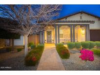 Charming home exterior with a covered porch, landscaped yard, and brick walkway at twilight at 20906 E Macaw Dr, Queen Creek, AZ 85142