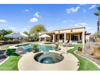 Inviting backyard pool area with a spa, lush landscaping, and patio seating at 21141 E Stirrup St, Queen Creek, AZ 85142