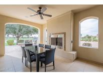 Covered patio featuring a dining table, outdoor fireplace, ceiling fan and scenic golf course views at 623 E Peach Tree St, Queen Creek, AZ 85140