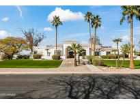 Stunning desert home with palm trees, lush green lawn, and circular driveway at 6700 E Caron Dr, Paradise Valley, AZ 85253