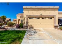 Tan home exterior featuring a well-manicured front lawn and a two-car garage at 8850 W Piute Ave, Peoria, AZ 85382