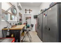 Well-lit workshop with functional workbench, tool storage, and climate control, ideal for hobbies at 11121 E Onza Ave, Mesa, AZ 85212